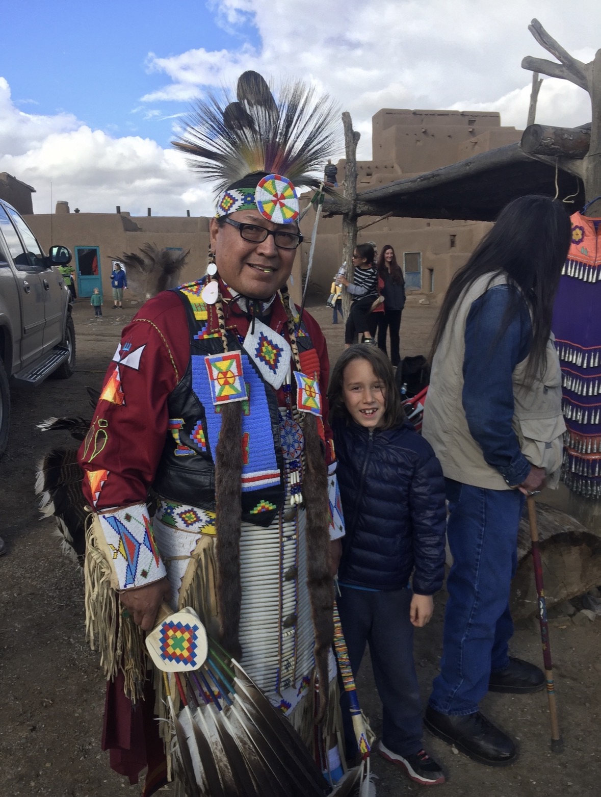 Young Robbie standing with a Lakota participant wearing Northern Plains traditional regalia