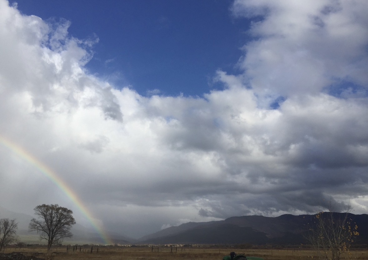 A rainbow descending from storm clouds across the valley near Taos Pueblo