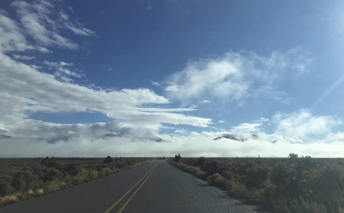 A road approaching cloud wrapped mountains near Taos Pueblo