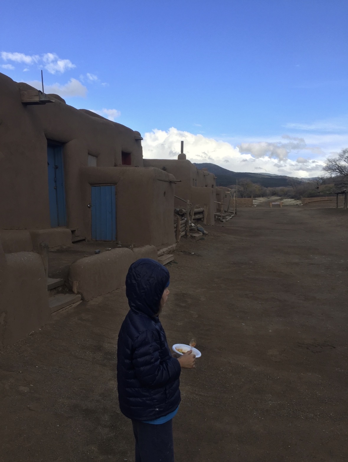 Young Robbie eating beside the adobe homes at Taos Pueblo