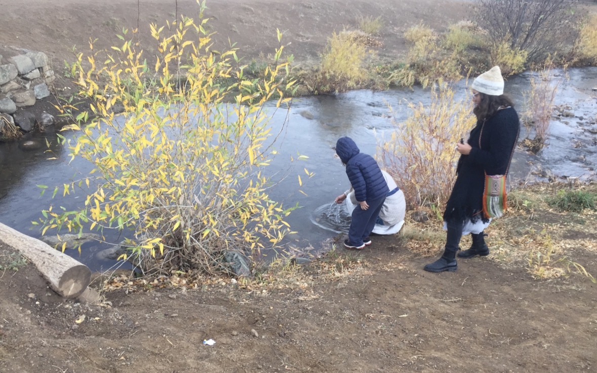Robbie and two adults beside the river at Taos Pueblo in autumn